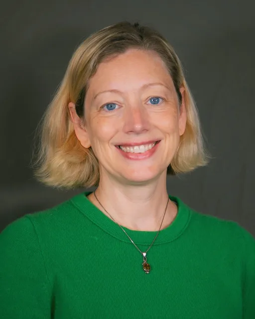 Female with chin-length, blonde hear wearing a green shirt and necklace