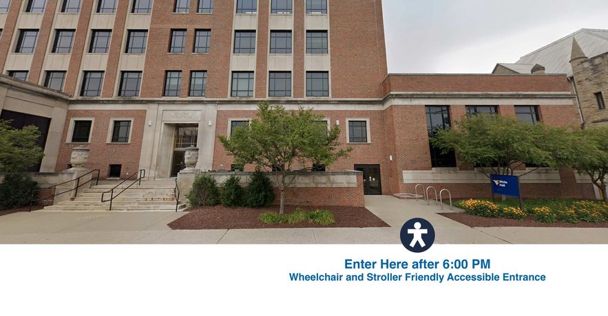 The front of White Hall, a brick building that is three stories tall. The planetarium entrance that is accessible and stroller friendly is shown next to the blue sign and bike rackers. You muster enter here after 6:00 PM